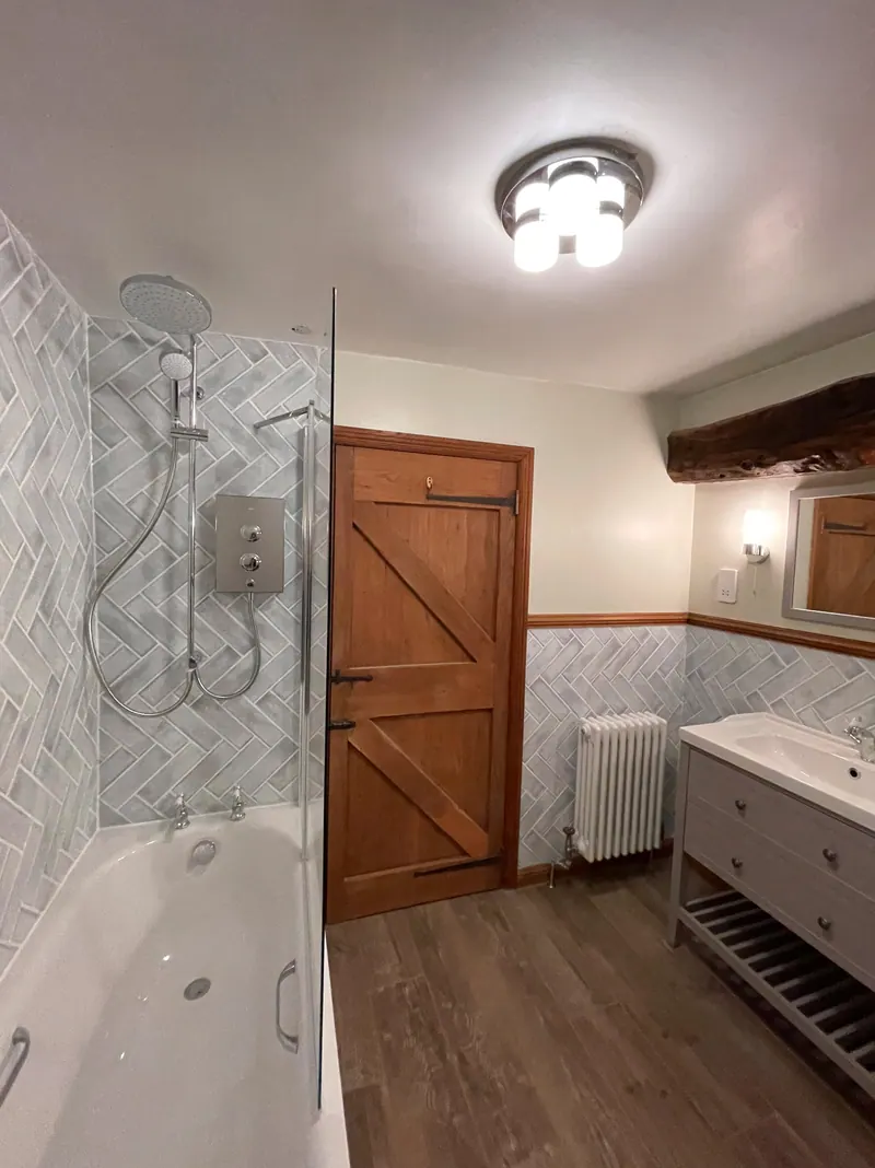 Bathroom with herringbone wall tiles, shower bath and freestanding vanity