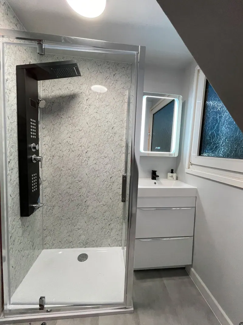 Shower room with glass enclosure, shower tower and illuminated mirror