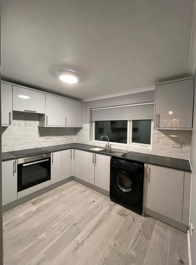 Light grey gloss kitchen with herringbone tiled splashback