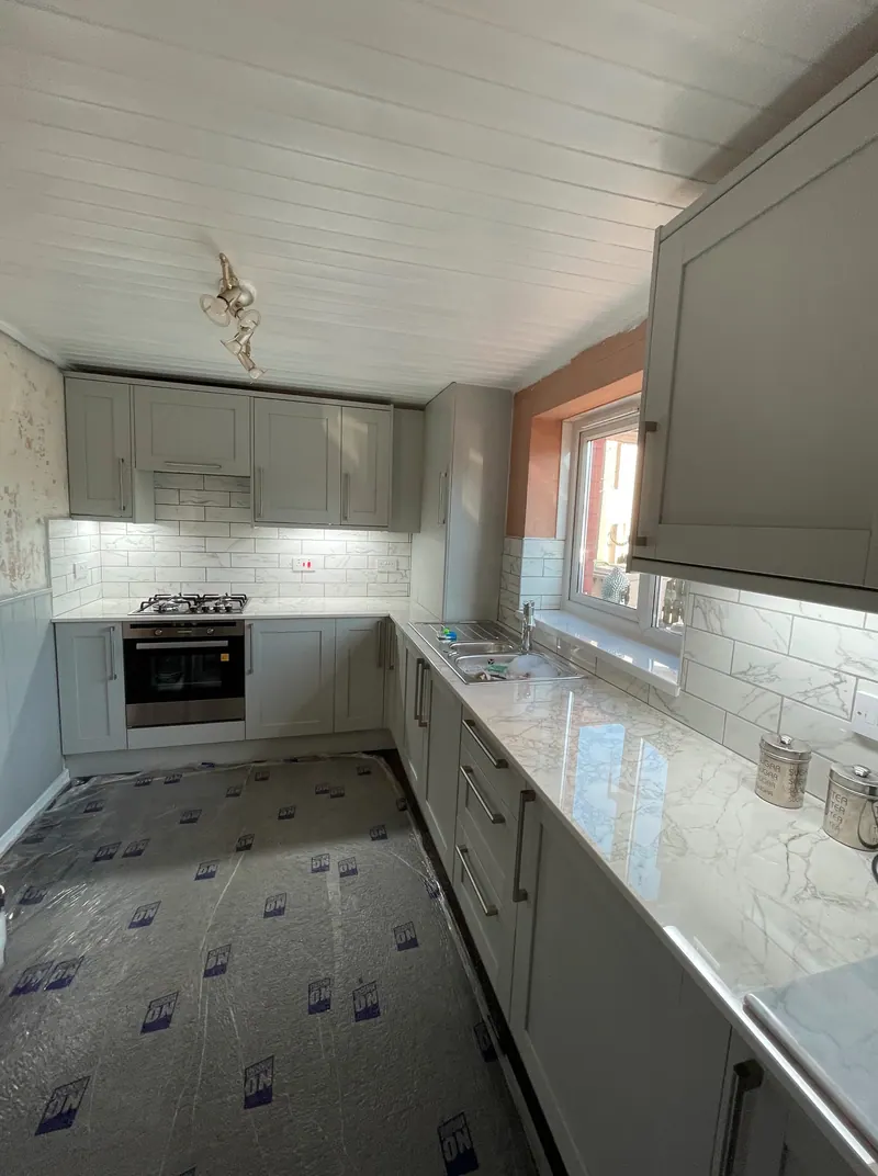 Grey shaker kitchen with metro tiles, floor protection still down at handover
