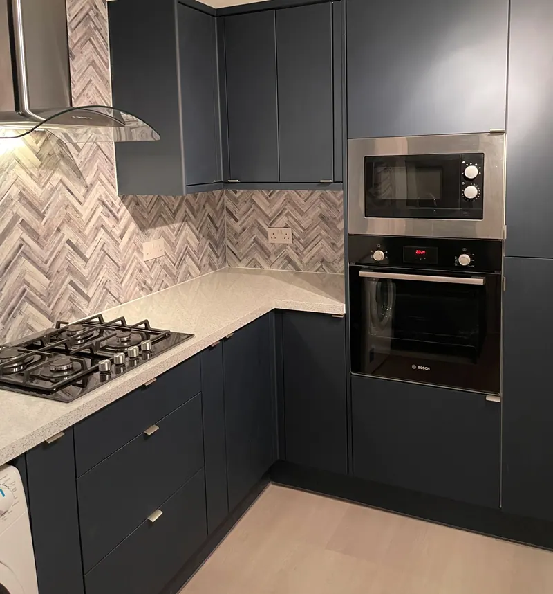 Navy shaker kitchen with herringbone marble splashback and integrated ovens